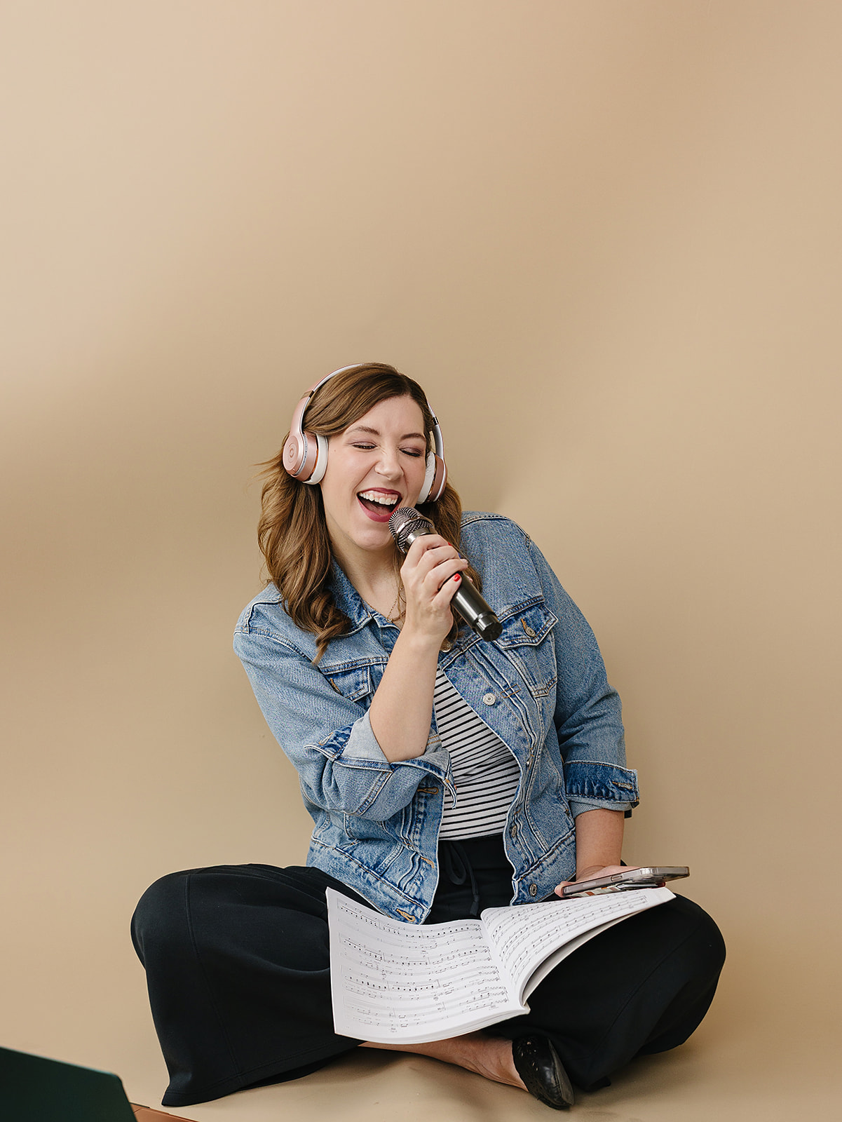 Alyssa singing into a microphone with headphones and sheet music